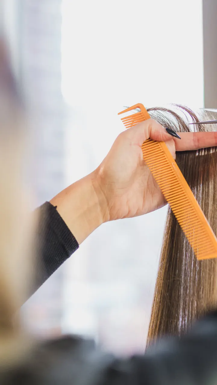 Cabeleireira a pentear cabelo comprido com um pente laranja
