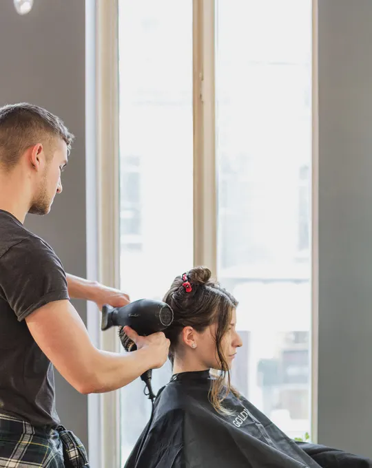 Cabeleireiro a secar o cabelo de uma cliente